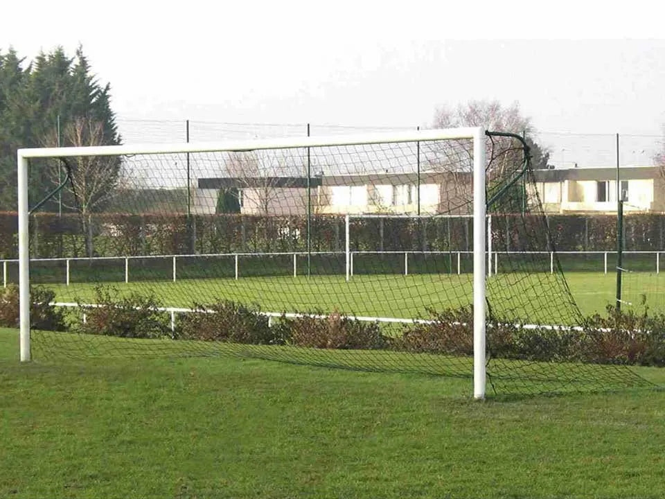 Filet pour but de football installé sur un terrain en herbe, avec structure blanche et filet robuste, idéal pour les matchs et les entraînements.